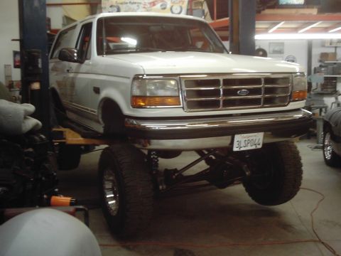 1978 Ford Bronco - This white Ford Bronco is shown on a lift in a garage, displaying its front 3/4 view.