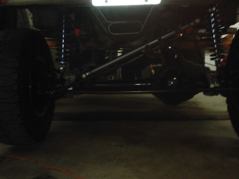 1978 Ford Bronco - A close-up view of a vehicle's undercarriage reveals its suspension system, including shocks and steering linkages.