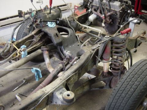 1991 Ford Bronco - The chassis and engine of a vehicle are disassembled, revealing the suspension and exhaust systems.
