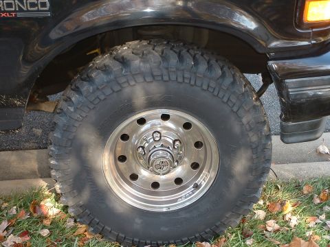 1994 Ford Bronco - Close-up of the front wheel and fender of a black 1994 Ford Bronco XLT.