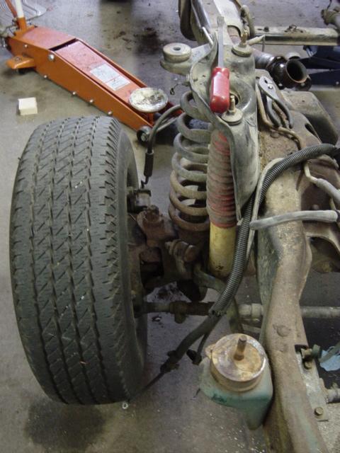 1991 Ford Bronco - Vehicle suspension and tire detail, with a floor jack visible.