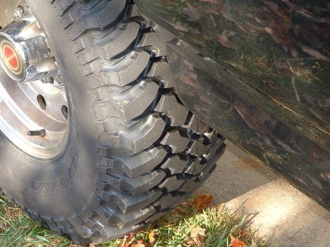 1994 Ford Bronco - Close-up of a 1994 Ford Bronco's off-road tire and side panel, showing a chrome hubcap.