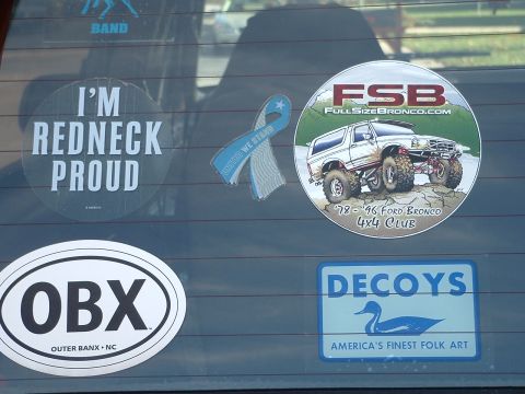 1994 Ford Bronco - Several stickers adorn the rear window of a vehicle, including one for a Ford Bronco club.
