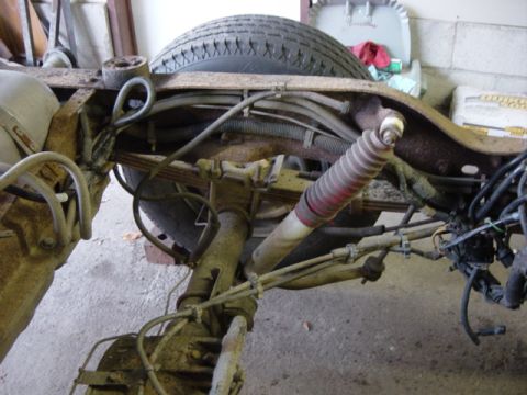 1991 Ford Bronco - Close-up view of the rear suspension components, including leaf springs and a shock absorber, on a vehicle frame.