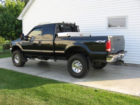 2001 Ford F-250 - This black Ford F-250 pickup truck is parked on a concrete driveway in front of a white house.