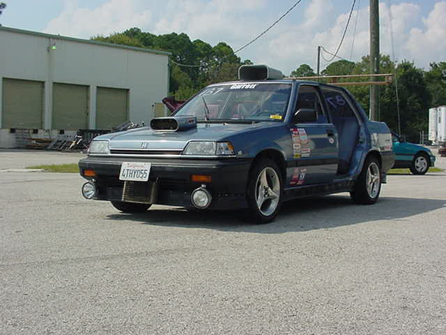 Blue sedan with hood scoop and racing decals, front view