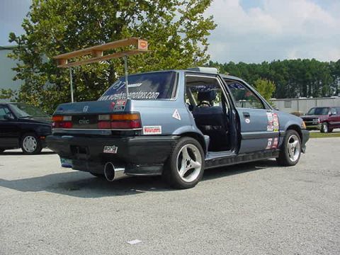 1996 Ford Probe - A blue Honda Civic, covered in racing decals, is parked outdoors with its doors open.