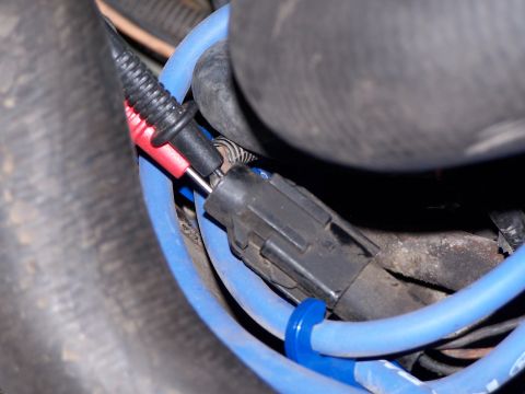 1986 Ford Bronco - Diagnostic tool probes a vehicle's engine wiring harness, indicating a repair or inspection process.