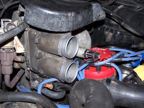 1986 Ford Bronco - Close-up view of an engine's throttle body and an MSD ignition distributor with blue spark plug wires.
