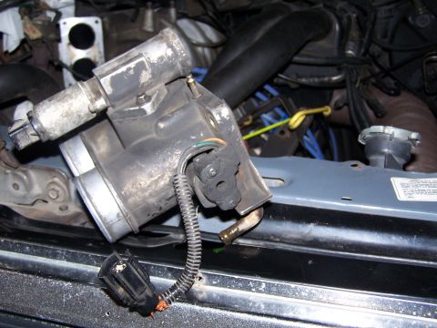 1986 Ford Bronco - Throttle body assembly removed from engine bay, showing disconnected electrical connector and hose.
