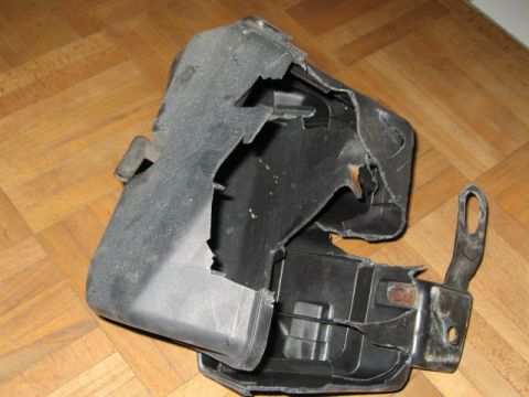 1992 Ford Crown Victoria - This is a damaged plastic car part with a metal bracket, shown on a wooden floor.
