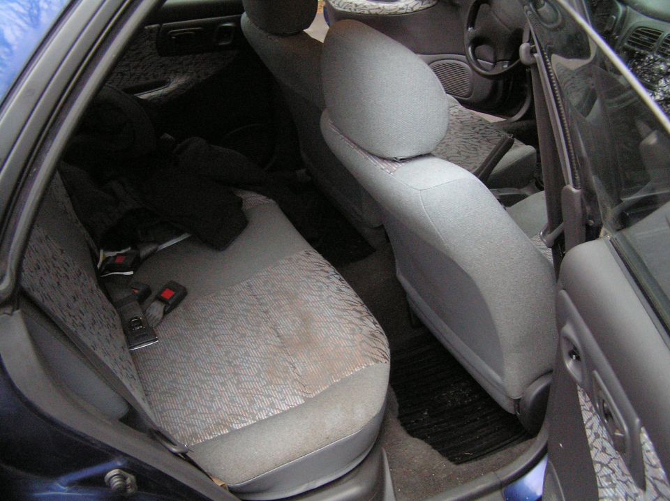 Gray cloth rear seat of a blue Subaru seen through the open rear door