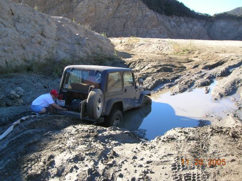 1985 Ford Bronco - A person attempts to free a Jeep Wrangler that is stuck in a muddy ditch, with a date stamp of November 20, 2005 visible.