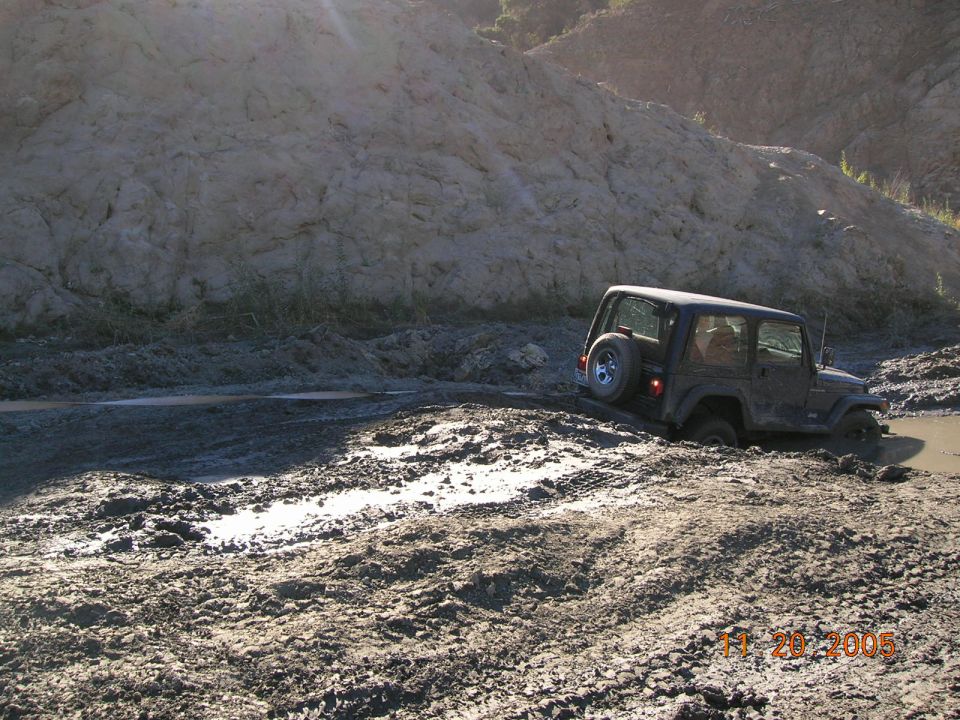 Jeep Wrangler stuck in mud, rear tire visible