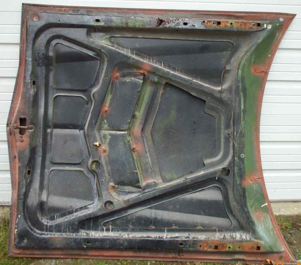 Underside of a green car hood with rust and wear