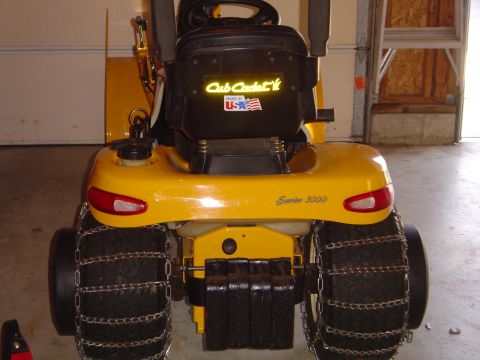 1978 Ford Bronco - Rear view of a yellow Cub Cadet Series 3000 lawn tractor parked in a garage, showing the black seat with Cub Cadet and Made in USA decals,…