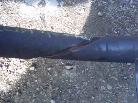 1995 Ford Bronco - Close-up of a damaged metal pipe lying on the ground.