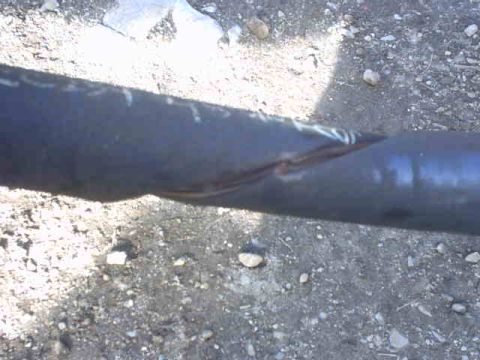 1995 Ford Bronco - A close-up of a damaged metal pipe lying on the ground.