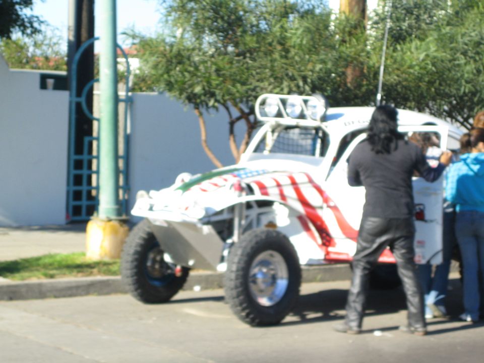 White off-road buggy with stars-and-stripes paint and a person standing beside it