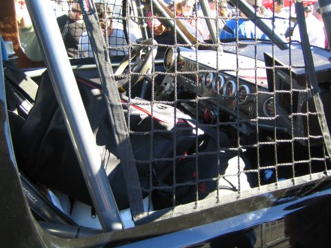 1990 Ford Bronco - cockpit of an off-road race truck is visible through window safety netting, revealing dash gauges and a steering wheel.