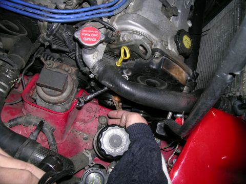 1993 Ford Probe - Close-up view of a vehicle's engine bay, focusing on a fluid reservoir cap and spark plug wires.