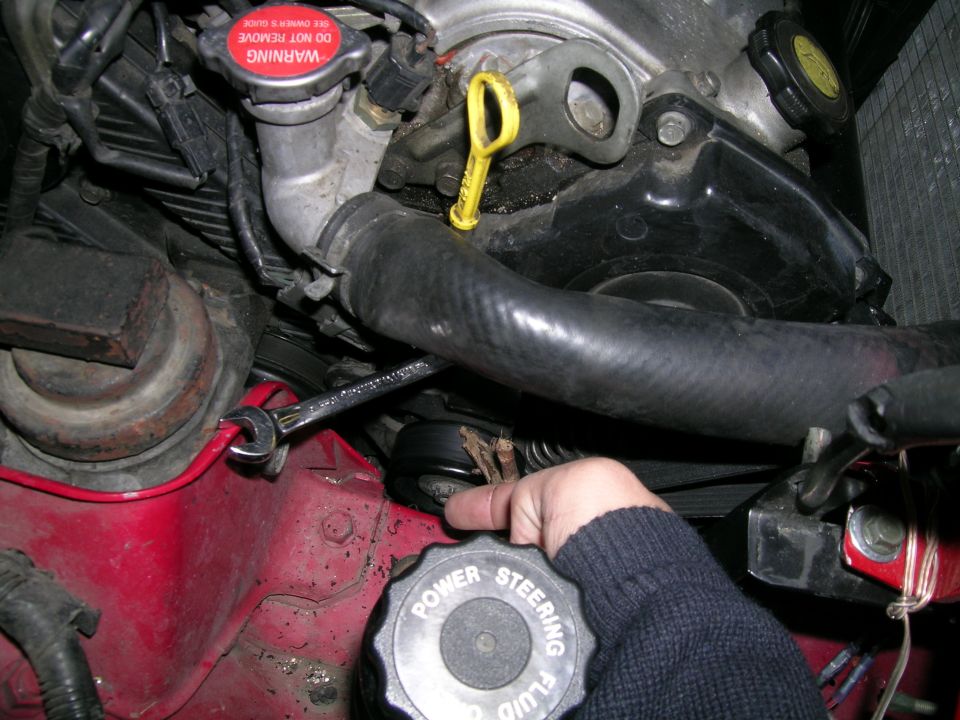 Engine bay with hand turning power steering fluid cap. Red fender visible