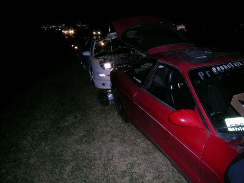 1993 Ford Probe - Two cars, a red Ford Probe and a white car, parked with hoods open at night.