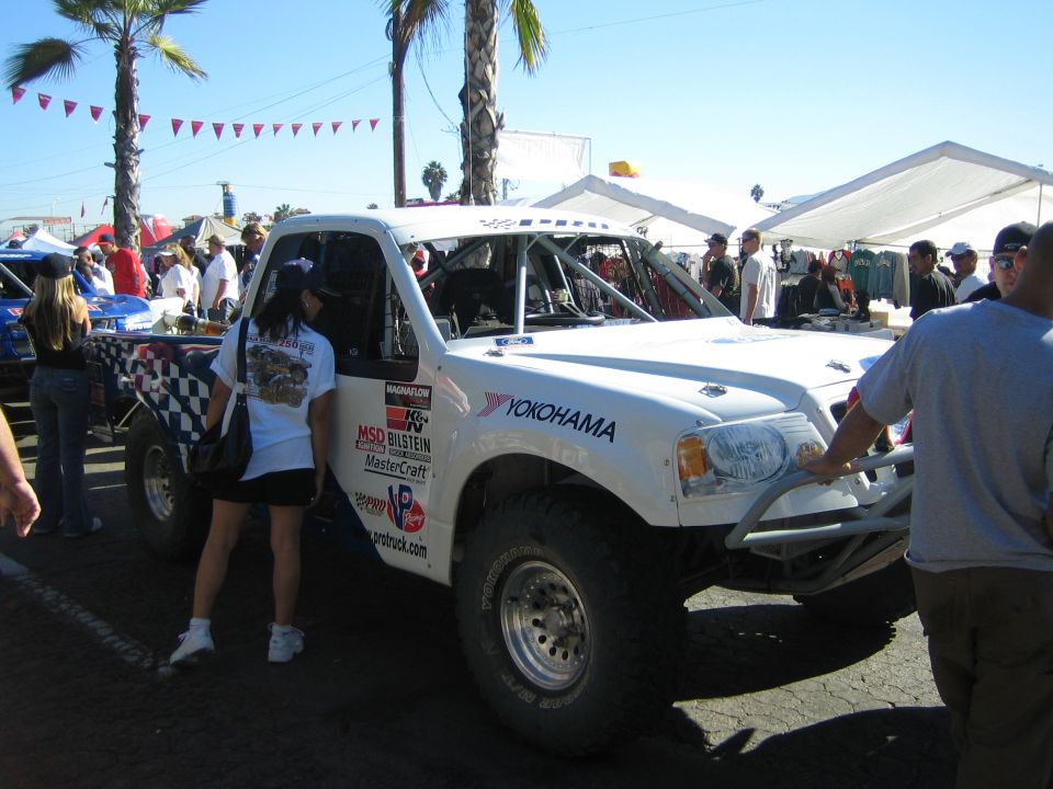White off-road race truck with Yokohama and MSD graphics being inspected by spectators under blue sky