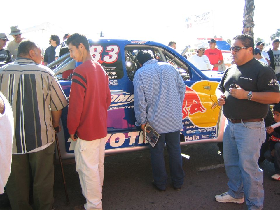 Blue number 83 Toyota off-road race car with USA-themed graphics inspected by spectators at an event