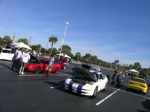 1993 Ford Probe - Several cars, including a 1993 Ford Probe, are displayed at an outdoor event under a clear blue sky.
