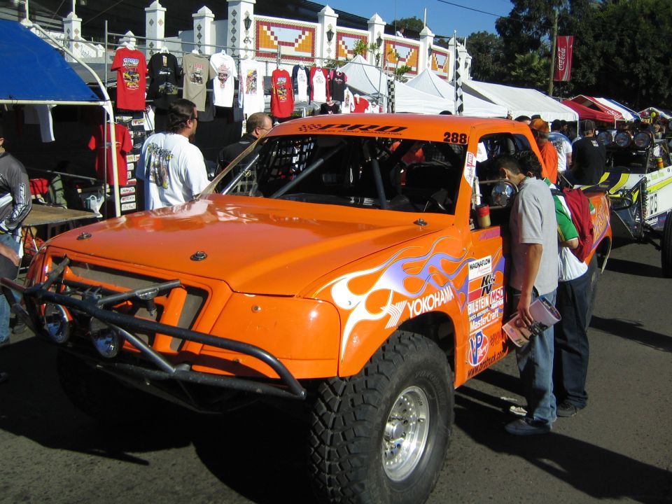 Orange off-road race truck number 288 with white flame graphics and Yokohama branding on big tires at an event