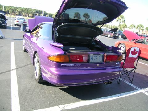 1993 Ford Probe - A purple 1993 Ford Probe GT is parked with its trunk and hood open, alongside other vehicles.