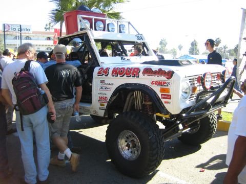 1990 Ford Bronco - white early Ford Bronco built as an off-road racer with 24 Hour Racing graphics, oversized tires and a roof light bar.