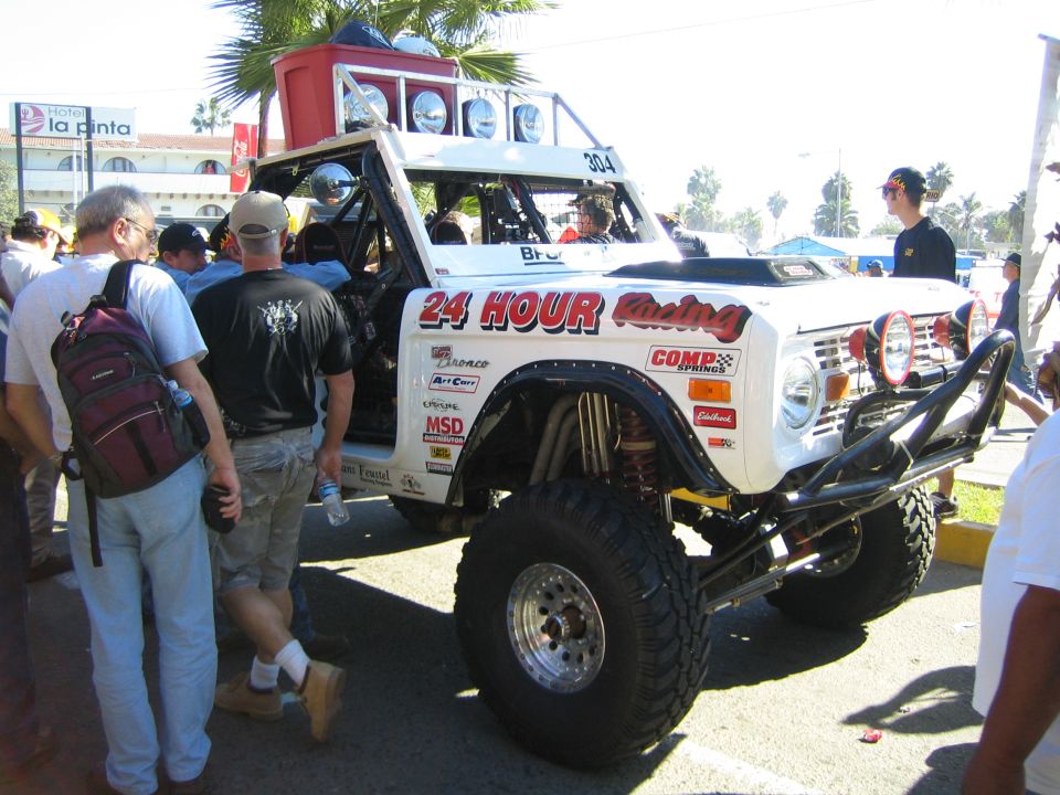 White early Ford Bronco off-road racer with 24 Hour Racing graphics and big tires