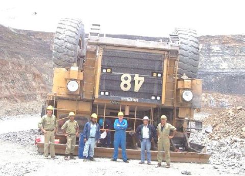 1991 Ford Bronco - A group of workers stand in front of a massive, overturned mining truck labeled "48" at a quarry.