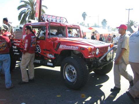 1990 Ford Bronco - red Hummer H1 off-road race truck, number 53, with a roof light bar and BFGoodrich graphics, among a crowd.