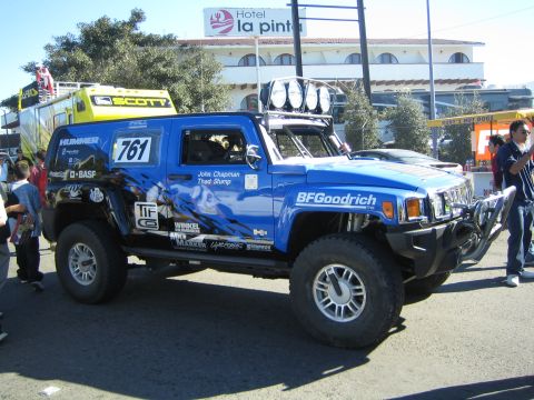 1990 Ford Bronco - blue Hummer H3 off-road race truck, number 761, with a roof light bar and HUMMER badging, parked in a lot.