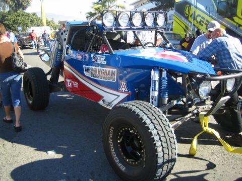 1990 Ford Bronco - blue and red tube-frame off-road buggy with Birmingham Motorsports livery and a five-pod roof light bar at an event.