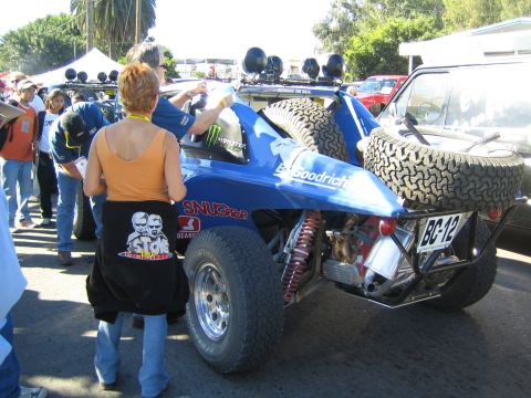 1990 Ford Bronco - Rear view of a blue tube-frame off-road buggy, BC-12, with a mounted spare tire and roof light pods, in a crowd.
