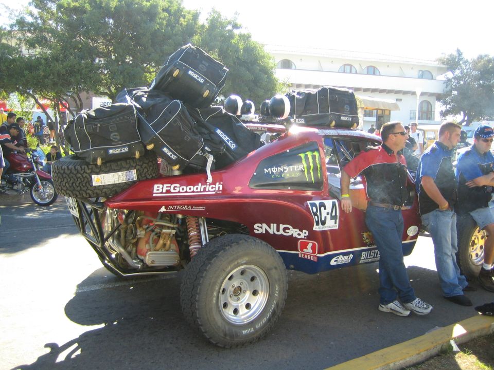 Dark red desert race buggy BC-4 loaded with gear bags and spares, Monster Energy decal
