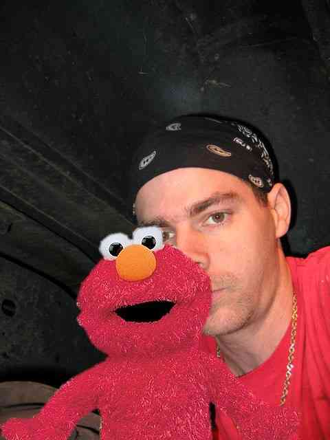 1968 Ford Mustang - A man poses for a selfie with a fuzzy Elmo puppet in front of his face.