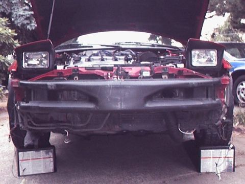 1996 Ford Probe - The front of a red car is shown with its hood open and bumper removed, supported by blocks.