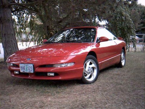 1996 Ford Probe - A red 1996 Ford Probe is parked outdoors next to a tree.