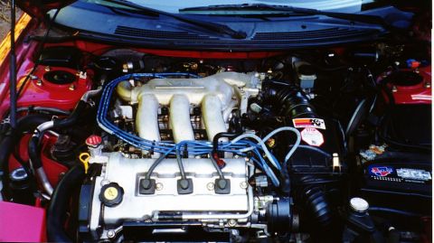 1996 Ford Probe - The engine bay of a red car, a V6 engine with blue spark plug wires and a K&N air filter sticker.