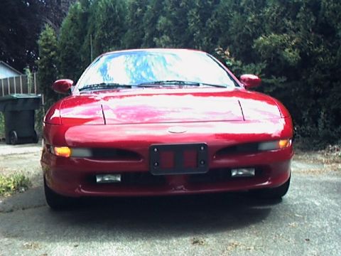 1996 Ford Probe - A red 1996 Ford Probe is shown from the front, parked in a driveway with a residential background.