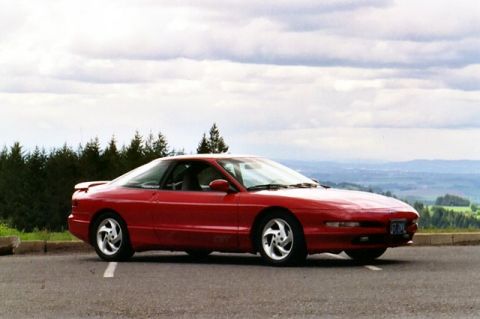 1996 Ford Probe - A red 1996 Ford Probe is captured from a three-quarter front view, parked at a scenic overlook.