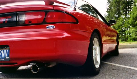 1996 Ford Probe - The rear of a red 1996 Ford Probe is visible from a low angle, with trees in the background.