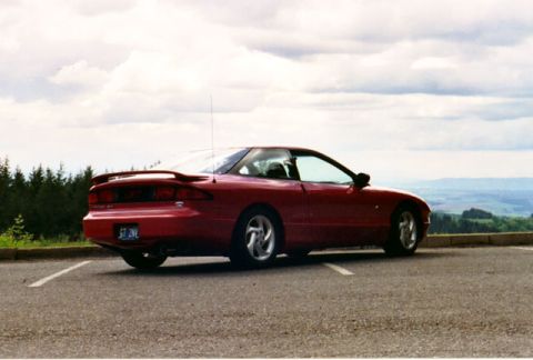 1996 Ford Probe - Rear view of a red 1996 Ford Probe parked outdoors with a scenic landscape in the background.
