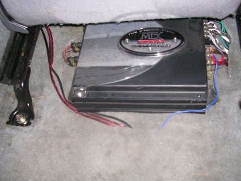 1996 Ford Probe - An aftermarket car amplifier is installed beneath the passenger seat, connected by various wires.