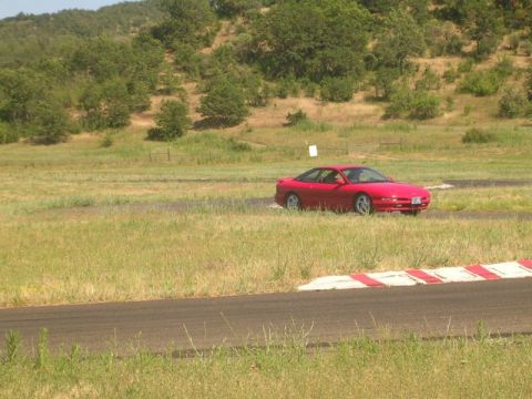 1996 Ford Probe - A red 1996 Ford Probe is seen on a racetrack with grassy surroundings.